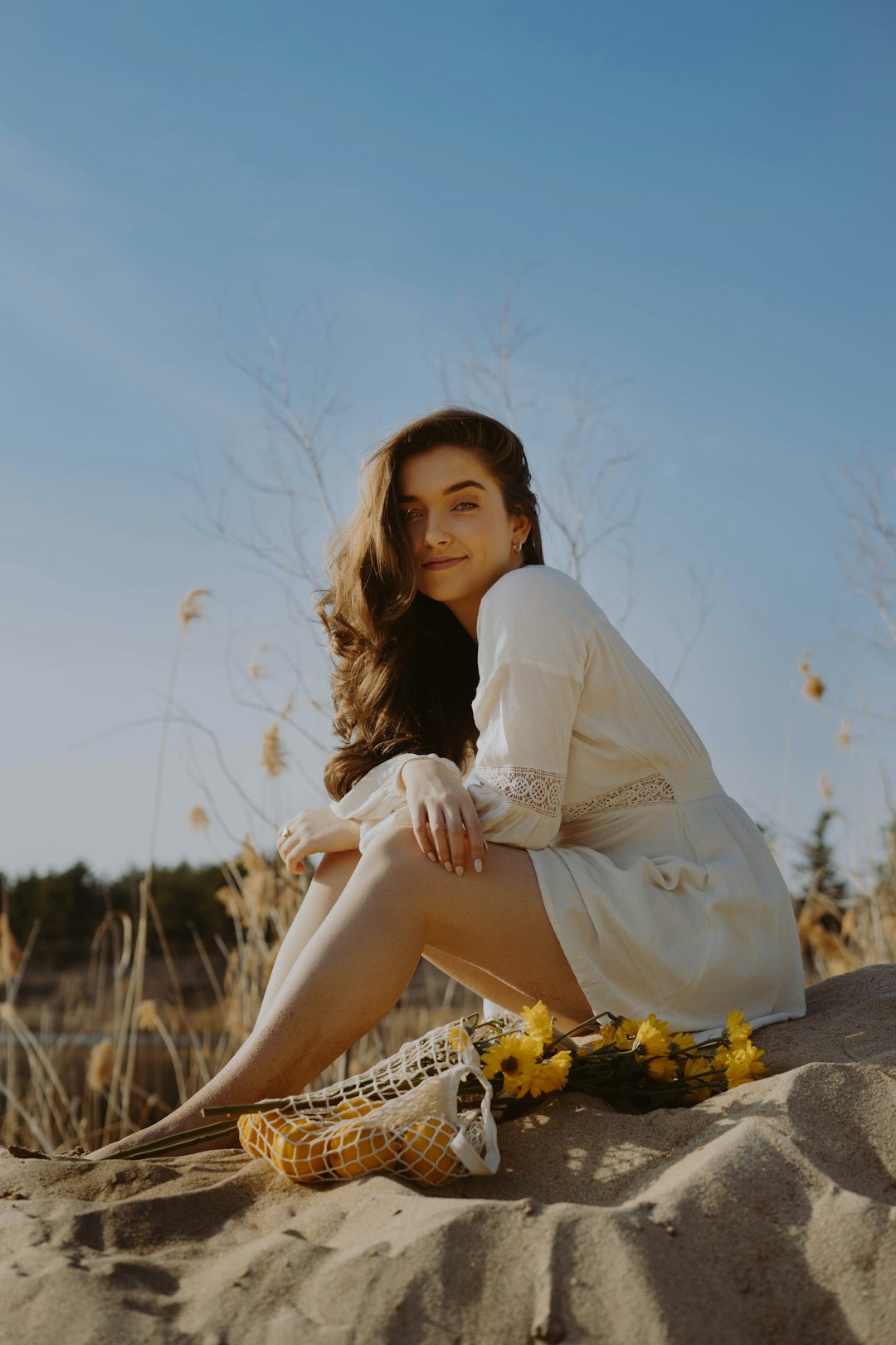 woman in white long sleeve shirt sitting on rock during daytime