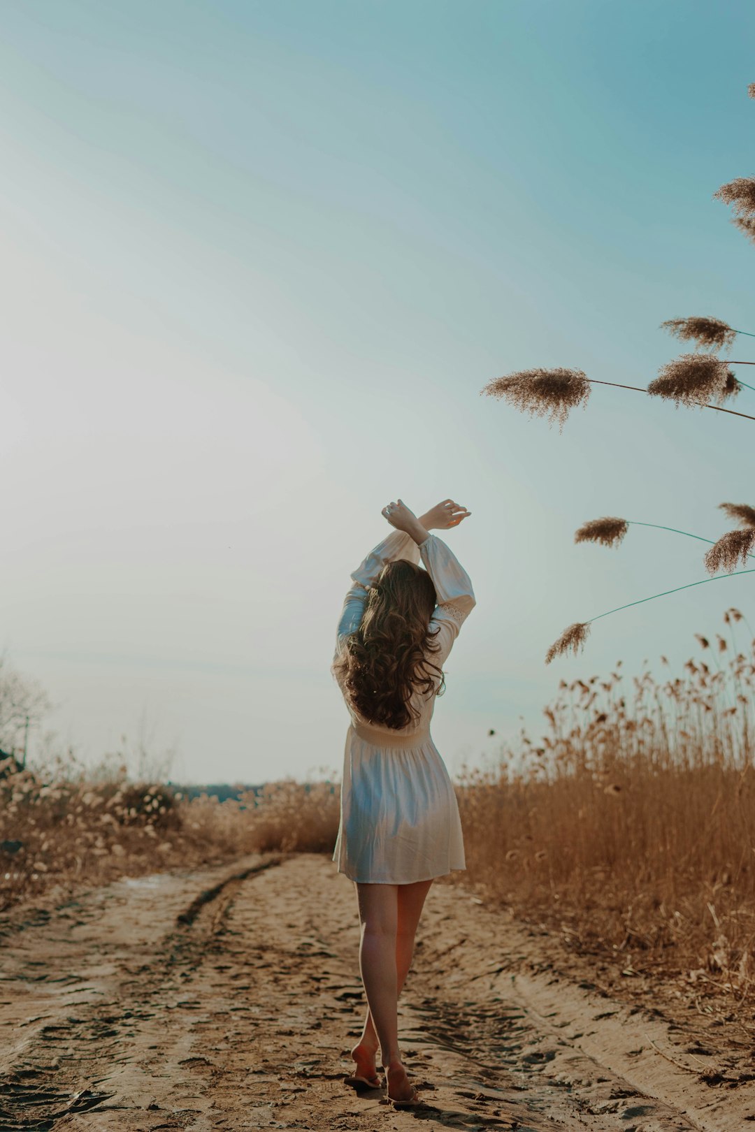 woman in white skirt standing on brown grass field during daytime