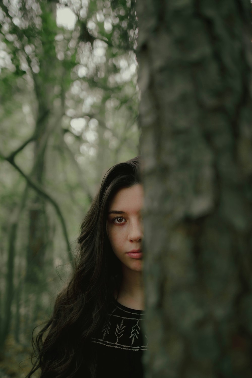 woman in black tank top standing near trees during daytime