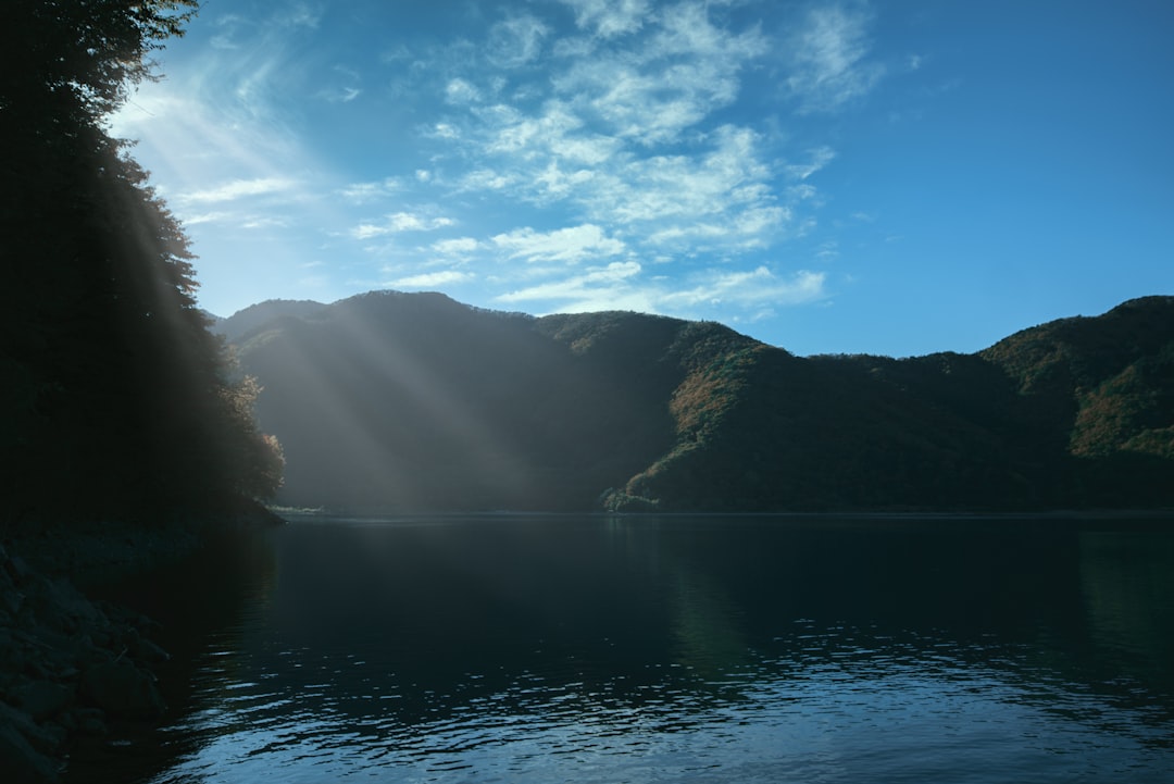 body of water near mountain under blue sky during daytime