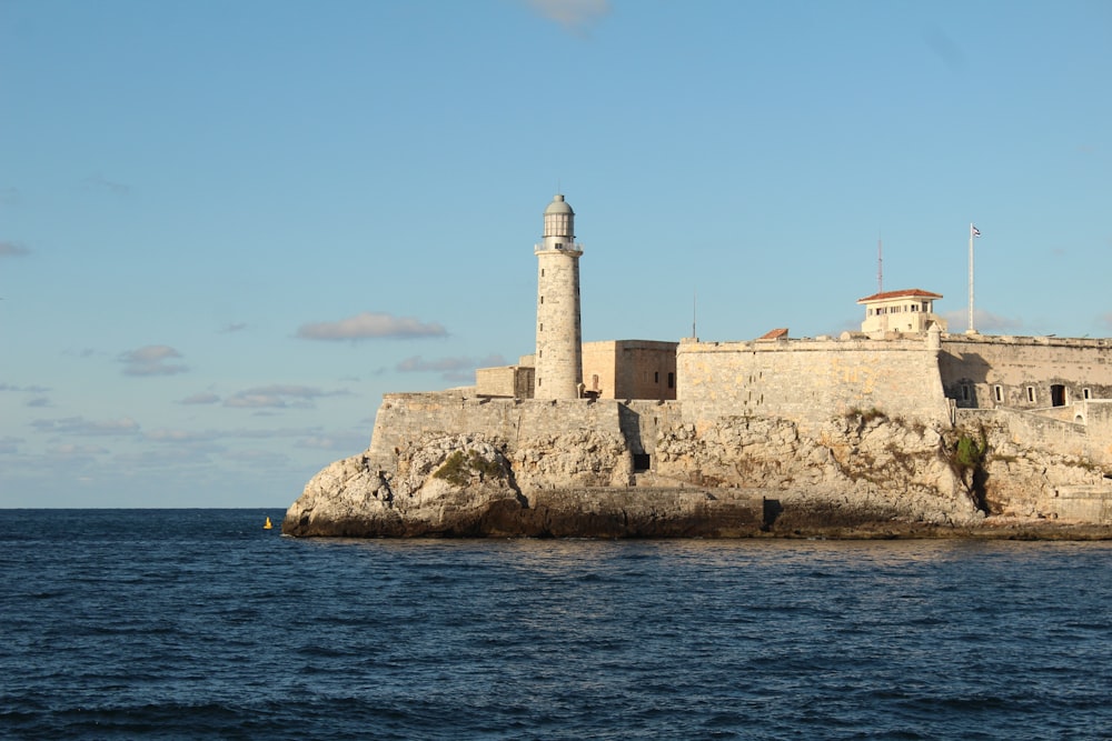 faro in cemento bianco vicino allo specchio d'acqua durante il giorno