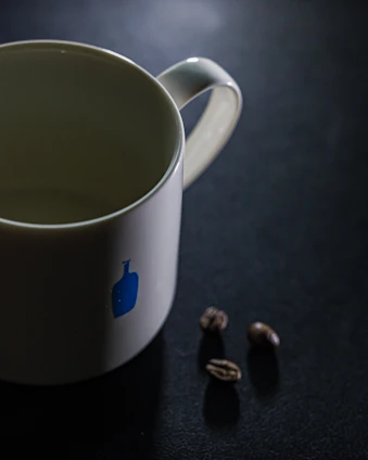 White ceramic mugs with personalized prints on a wooden table next to coffee beans