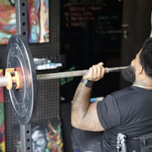 man in black crew neck t-shirt holding barbell