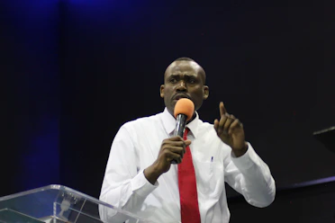 man in white dress shirt holding microphone