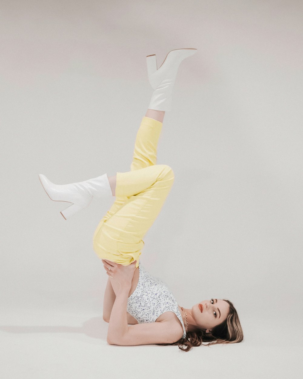 femme en débardeur floral blanc et rose et pantalon jaune