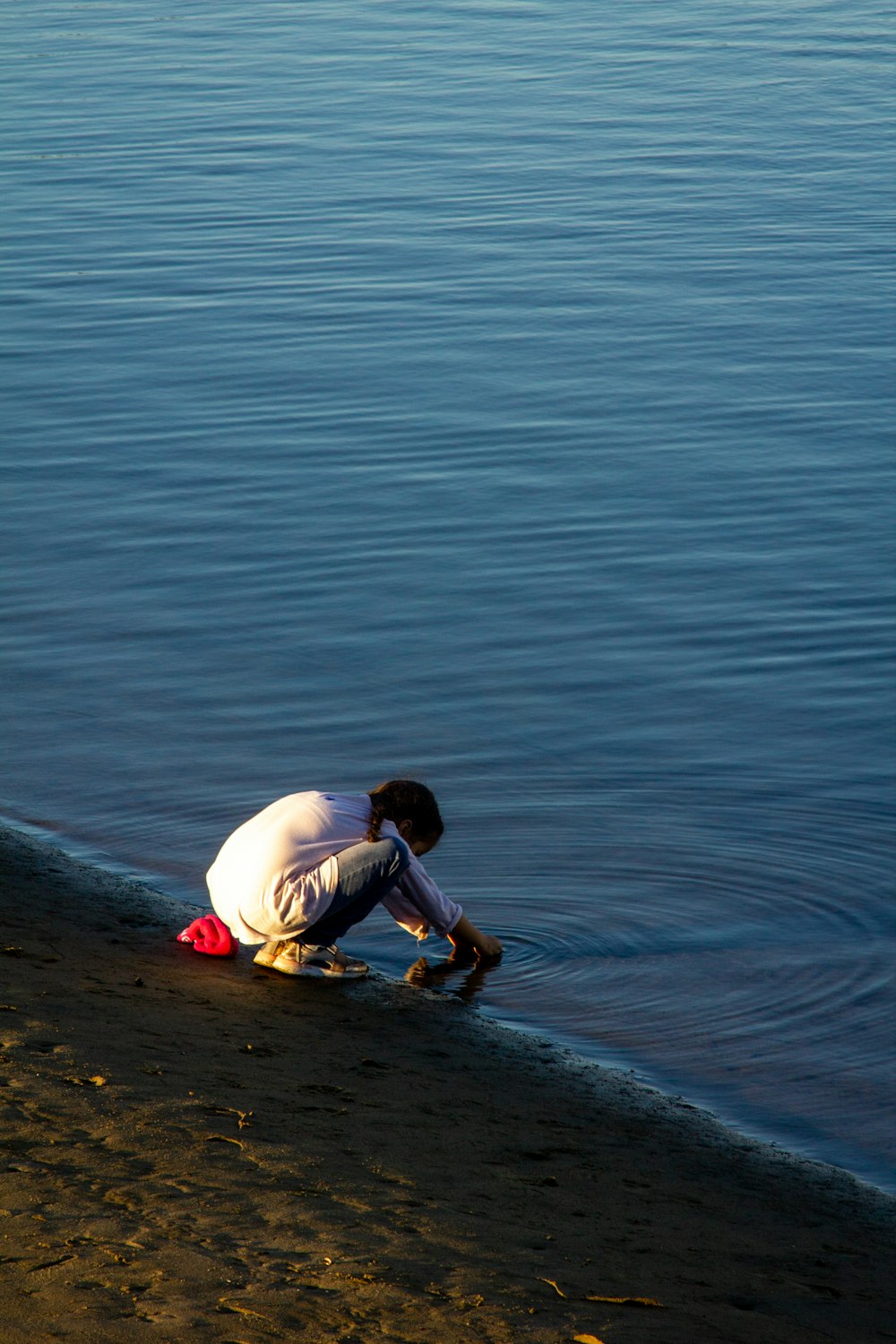 child in white shirt and brown shorts sitting on water during daytime