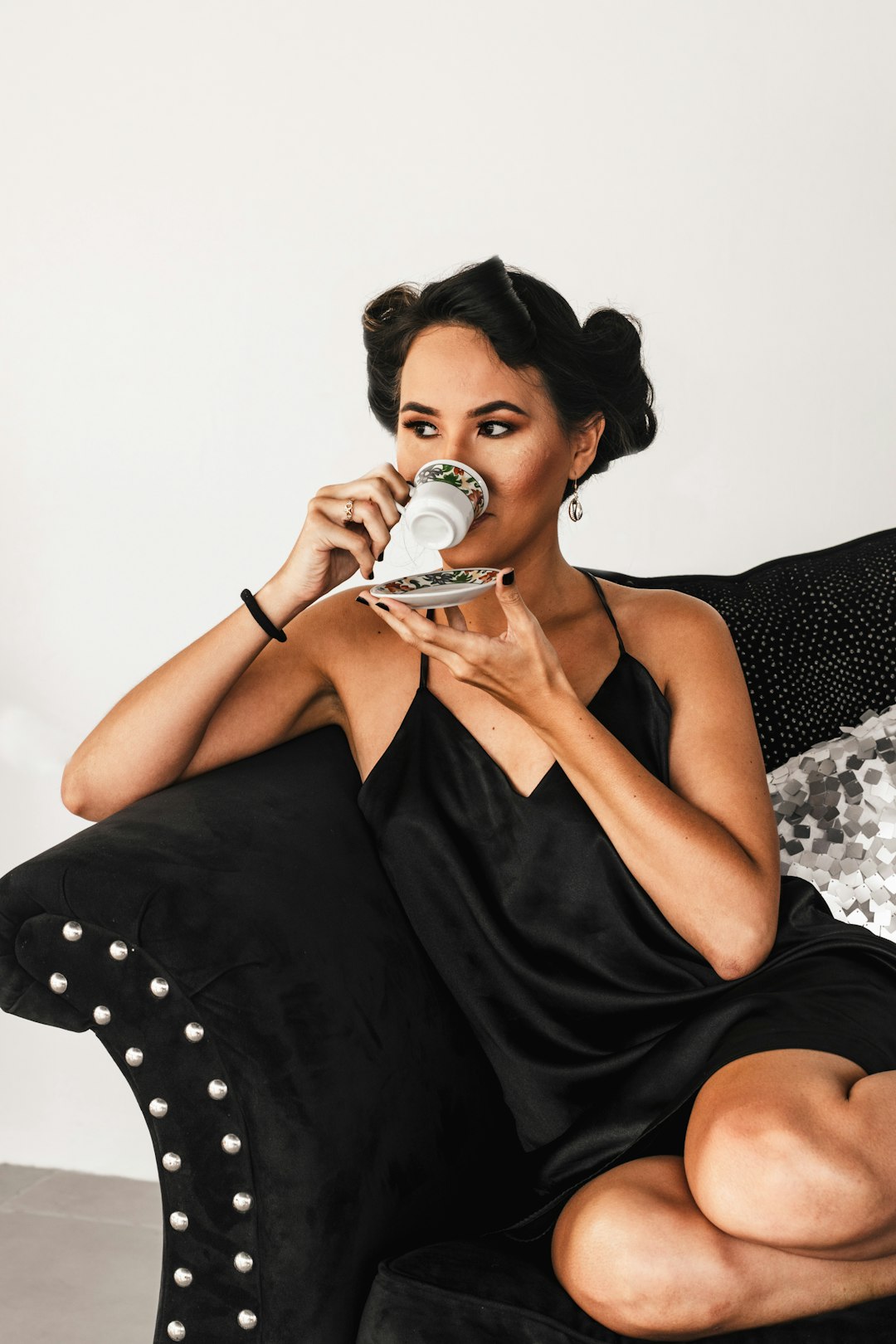woman in black sleeveless dress drinking from white ceramic mug