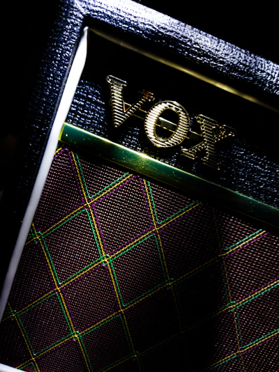 Close-up of a sleek black guitar amplifier with glowing neon green accents in a dark room.