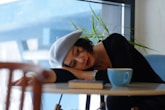 woman in black long sleeve shirt lying on white wooden table