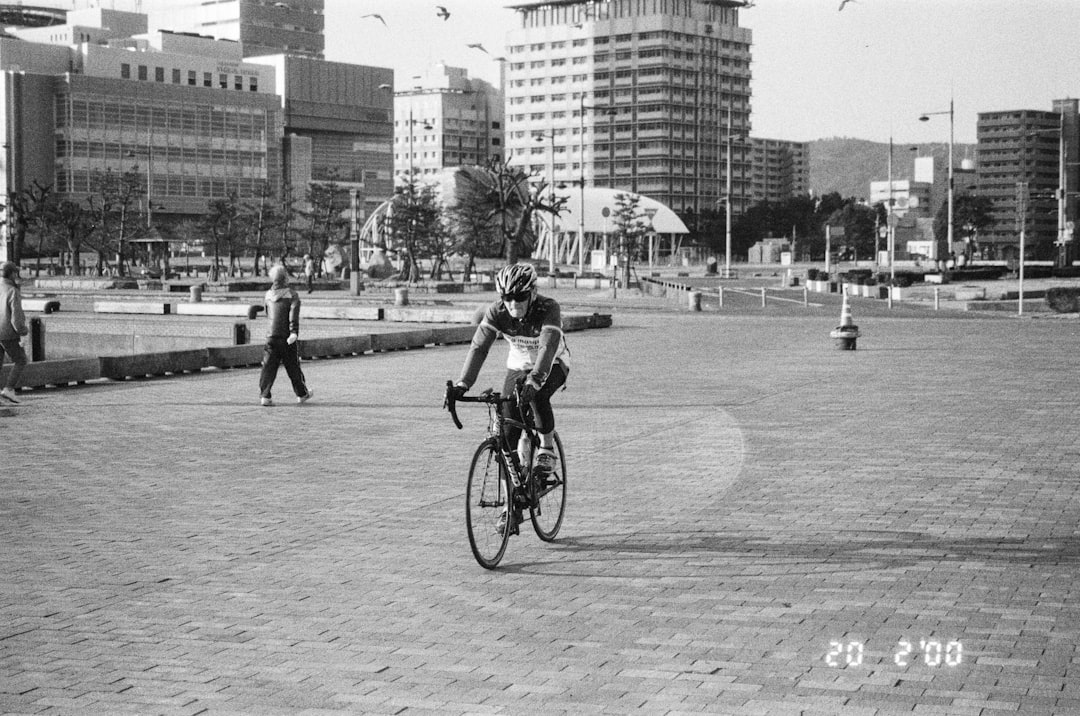 grayscale photo of man riding bicycle on road