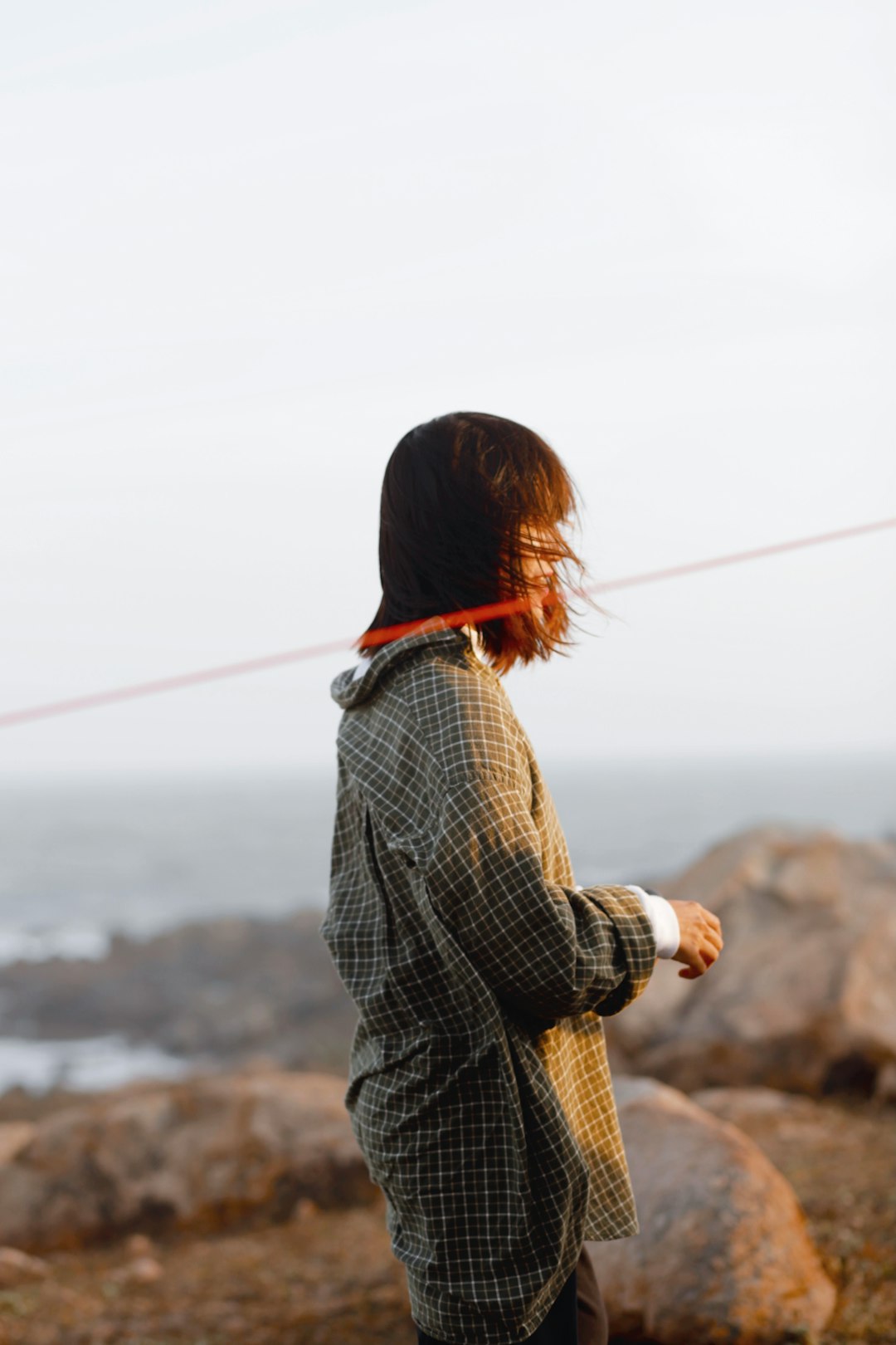 woman in black and white checkered long sleeve shirt standing on brown field during daytime