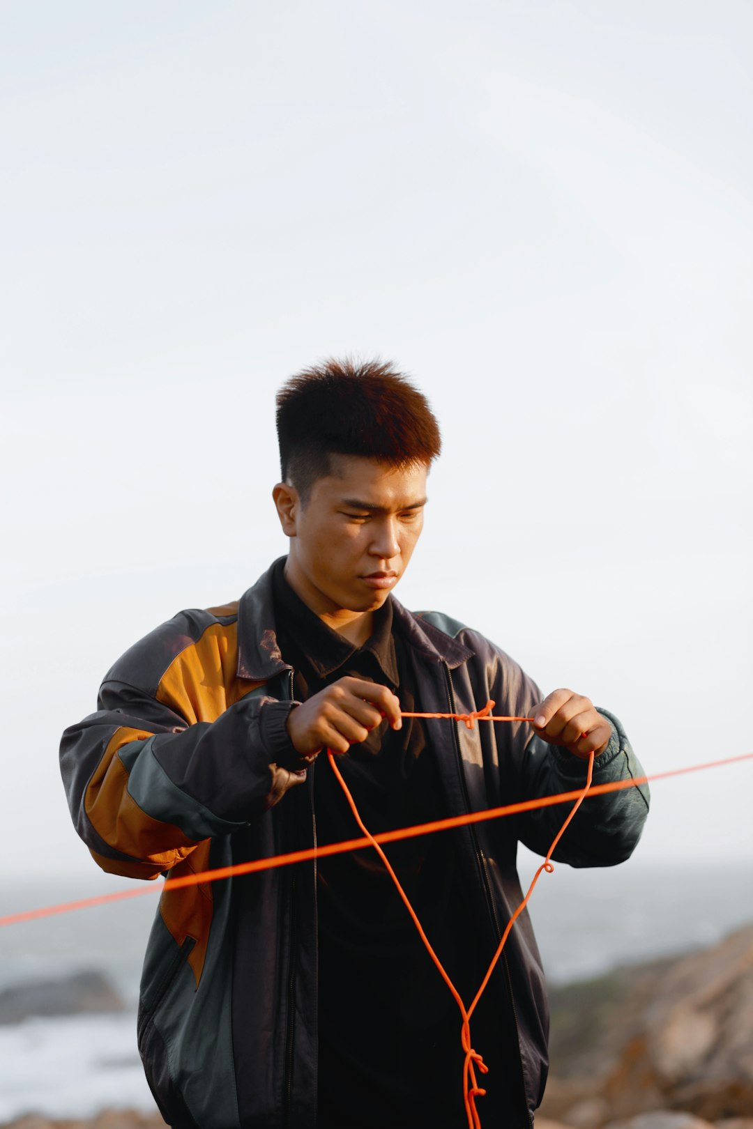 man in black and brown jacket holding red rope