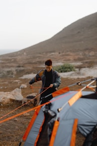 Close-up of skilled hands securing tent poles under bright desert sunlight.