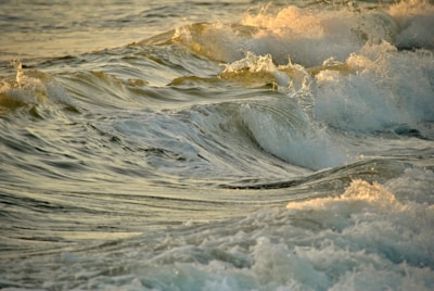 Waves in the ocean with sunlight gently illuminating the water, creating a mixture of dark and light patterns across the surface.