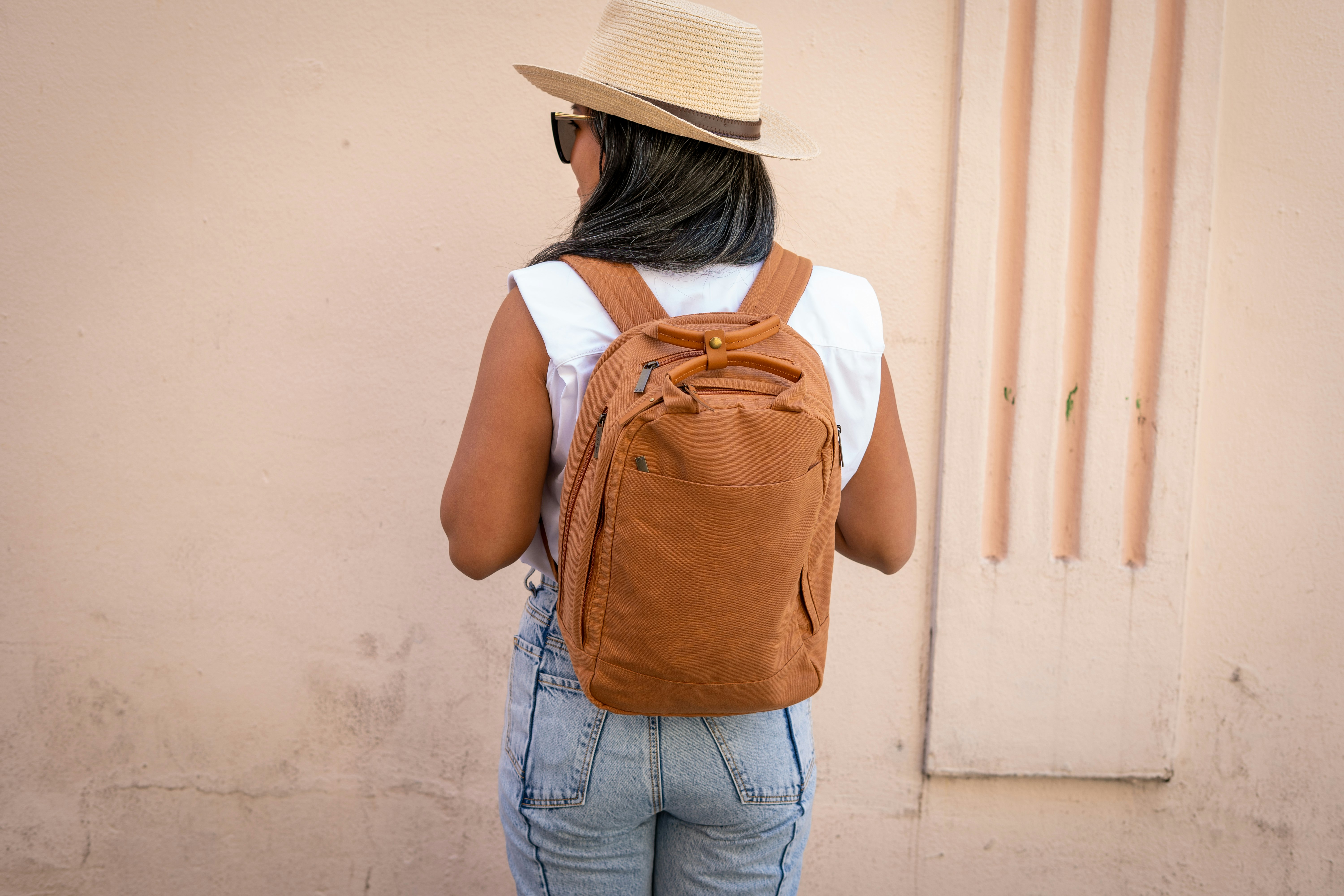 woman in white shirt and blue denim jeans with brown backpack