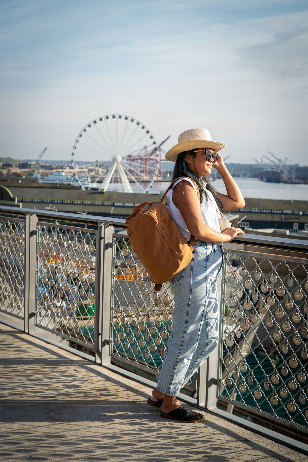 woman in brown leather backpack standing on bridge during daytime