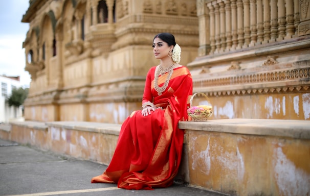 woman in red long sleeve dress sitting on gray concrete bench during daytime