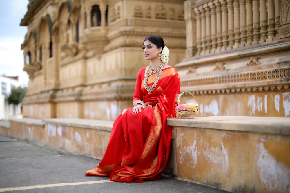 woman in red long sleeve dress sitting on gray concrete bench during daytime