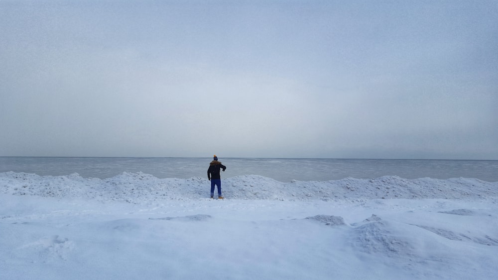 person in black jacket walking on snow covered field during daytime