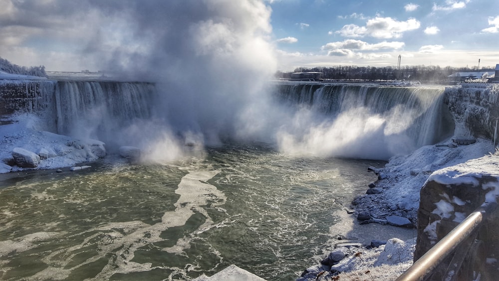 green and white water falls under blue sky during daytime