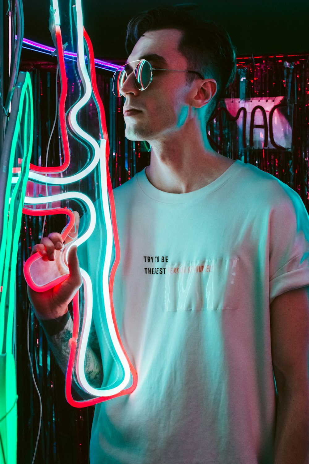 man in white crew neck t-shirt standing beside neon light signage
