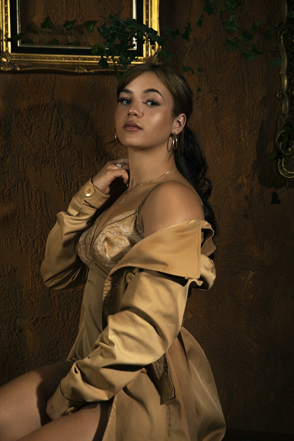 woman in beige spaghetti strap dress leaning on brown wall