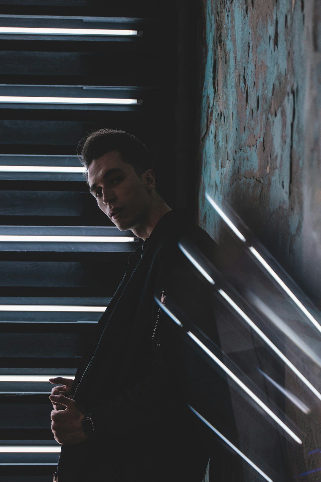 man in black jacket standing beside window