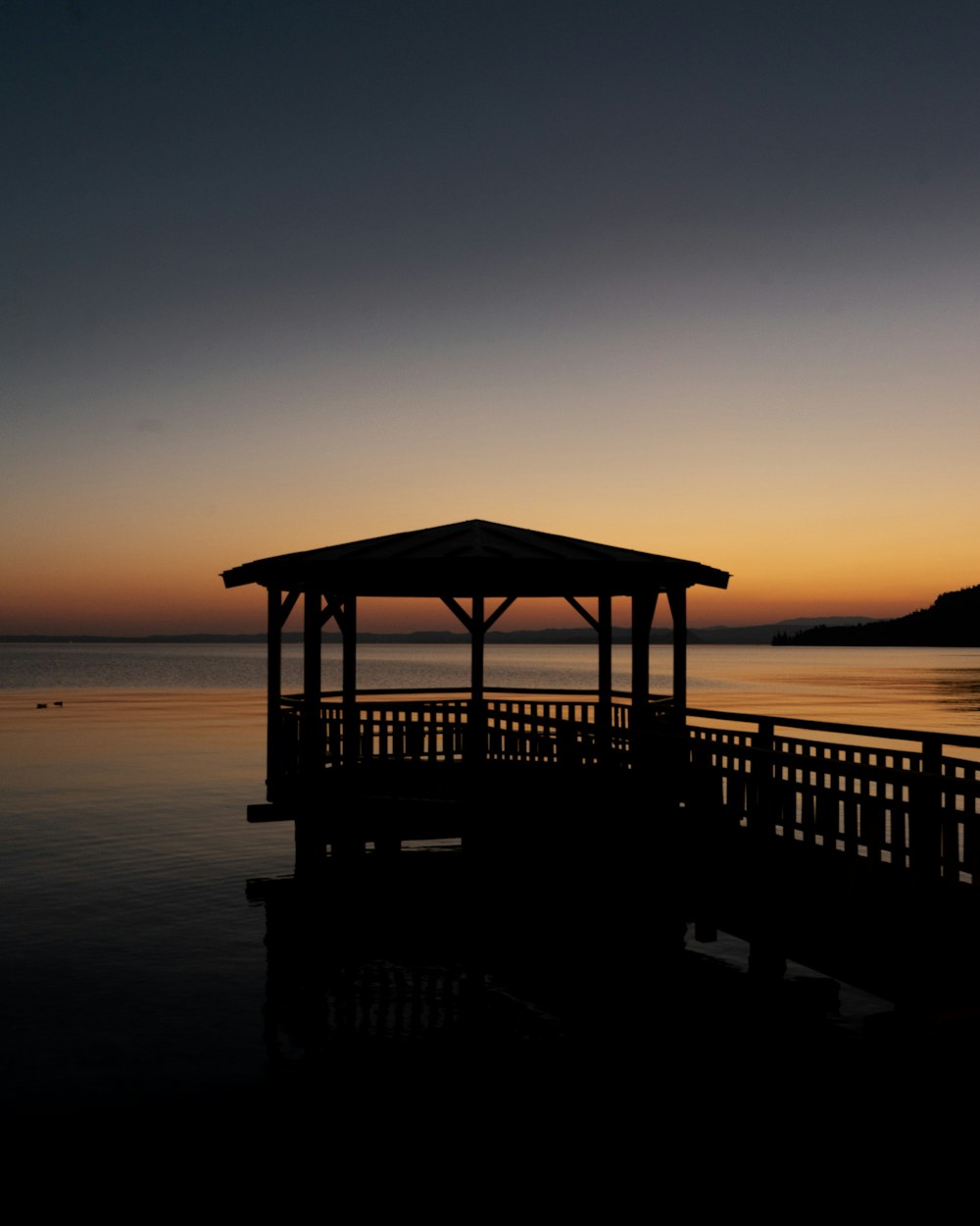 夕暮れ時の海岸の茶色の木製ガゼボ