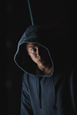 Dark, cinematic image showing a hoodie with a mysterious silhouette print glowing faintly in low light.