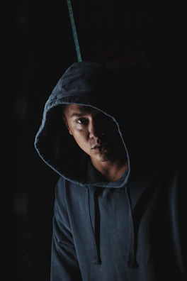 Dark, cinematic image showing a hoodie with a mysterious silhouette print glowing faintly in low light.