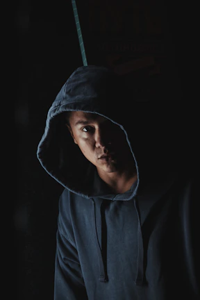 Matte black hoodie draped on a minimalist charcoal backdrop with soft shadows.
