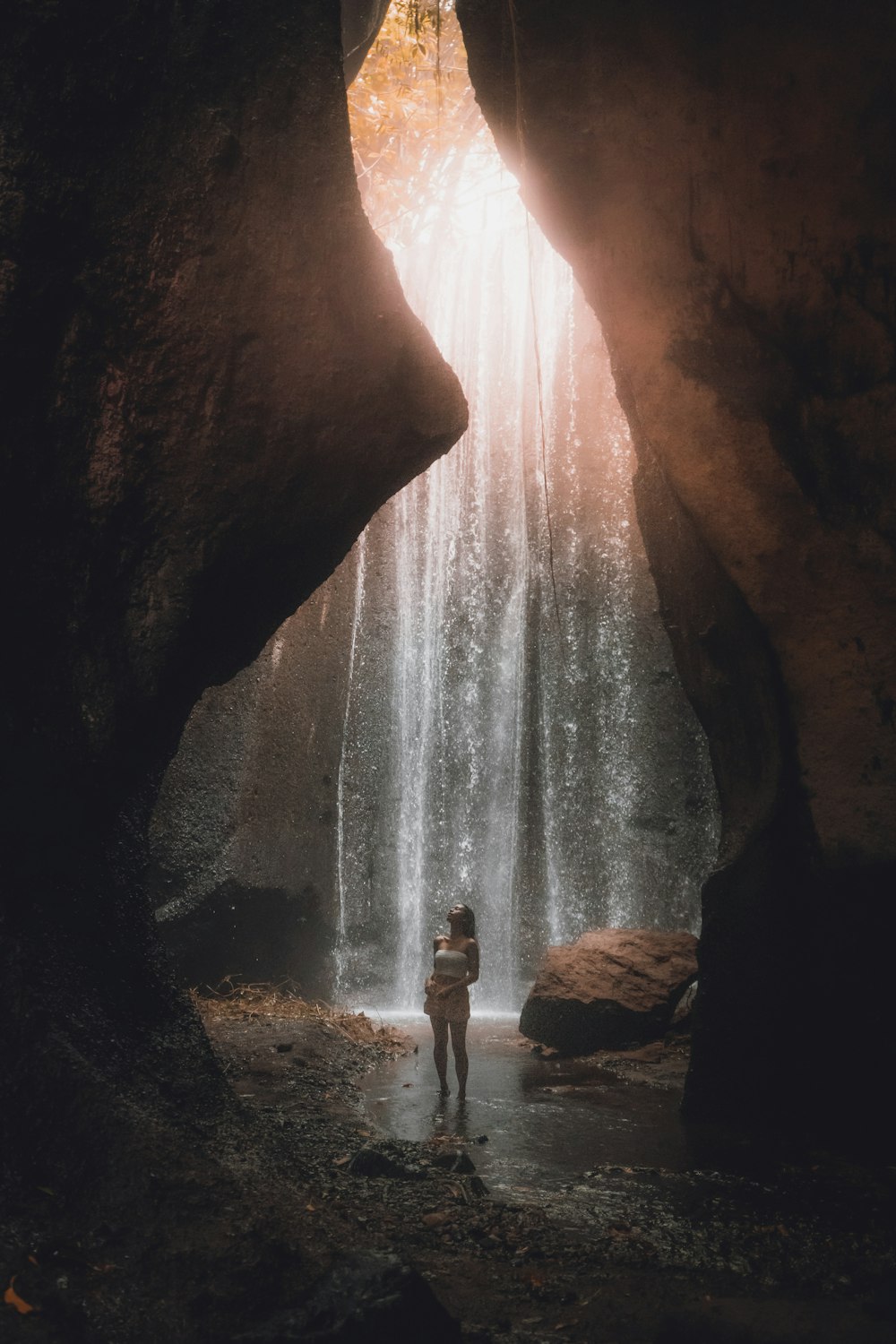 person standing on rock near waterfalls during daytime