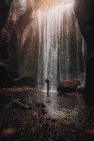 person standing on rock in front of waterfalls