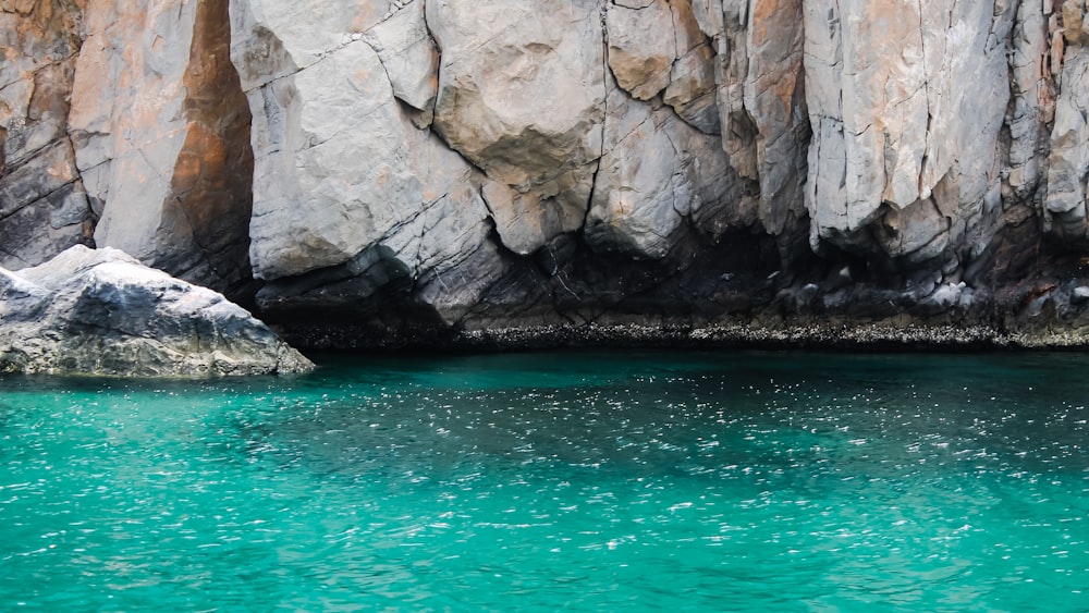 brown rocky mountain beside body of water during daytime