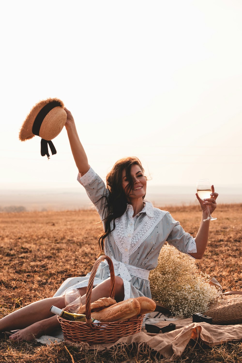 woman in white long sleeve shirt holding brown hat during daytime