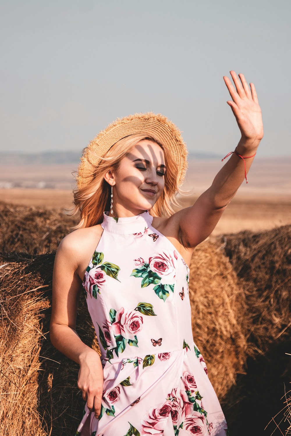 woman in white red and green floral sleeveless dress standing on brown field during daytime