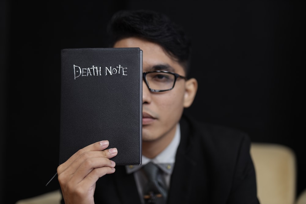 man in black suit holding black book
