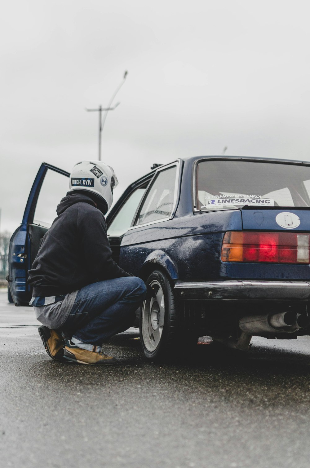 man in blue denim jeans sitting on black car