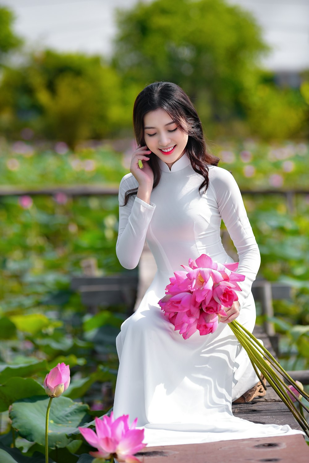 woman in white long sleeve dress holding pink flower