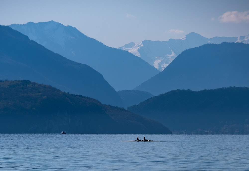 silhouette of 2 people riding boat on lake during daytime