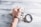 A hand wearing handcuffs is positioned on top of a pile of US dollar bills on a textured wooden surface. The handcuffs are open, suggesting recent use or potential freedom, and the hand is clenched into a fist.