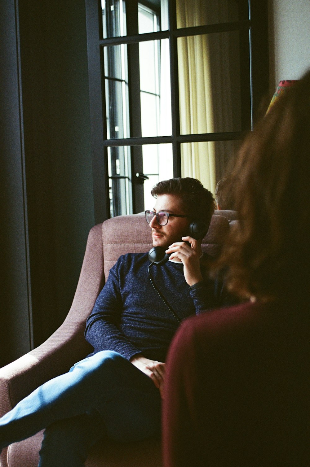 man in blue sweater sitting on brown sofa chair