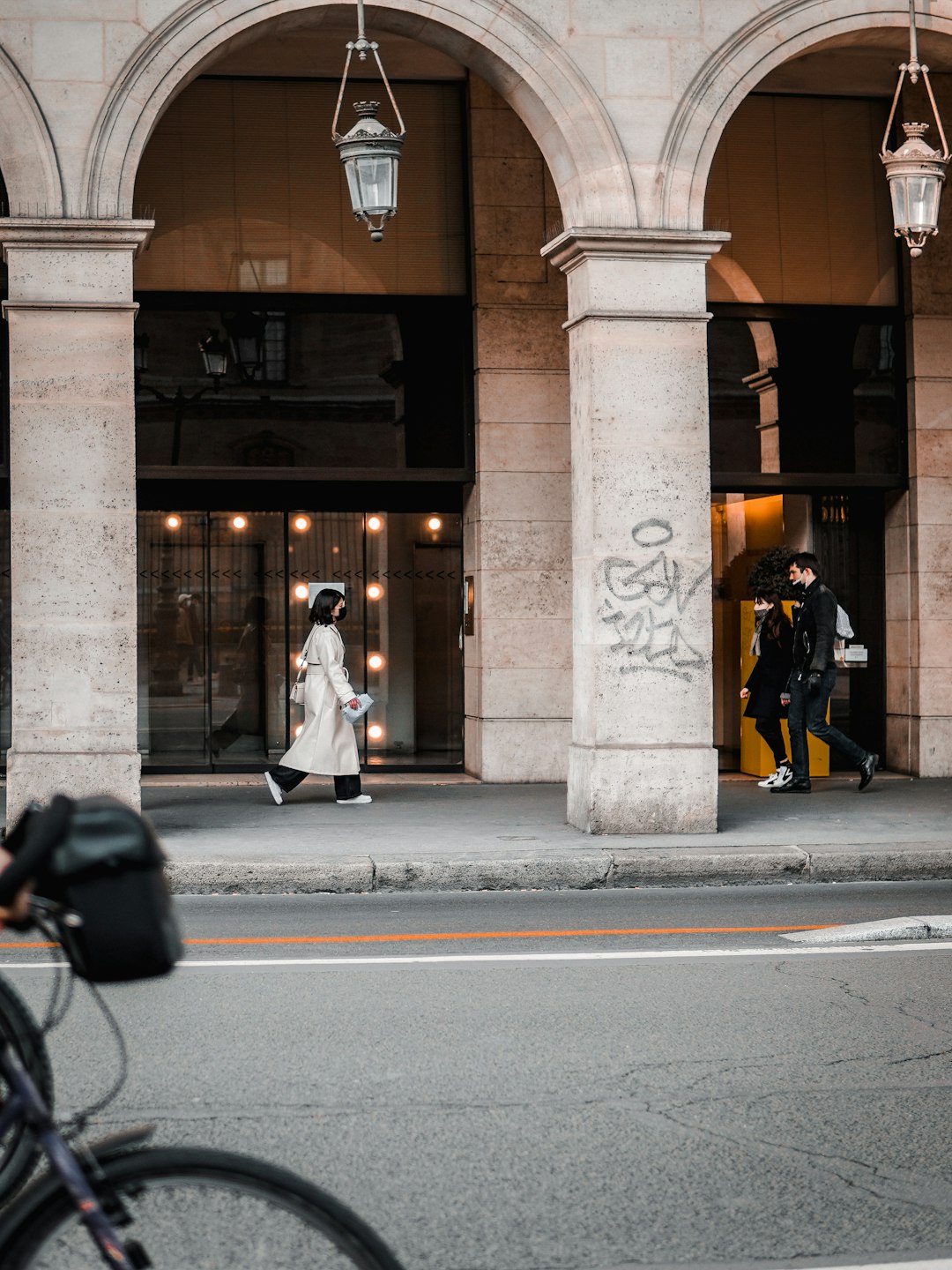 woman in white coat walking on sidewalk during daytime