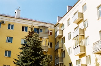 yellow concrete building near green trees under blue sky during daytime