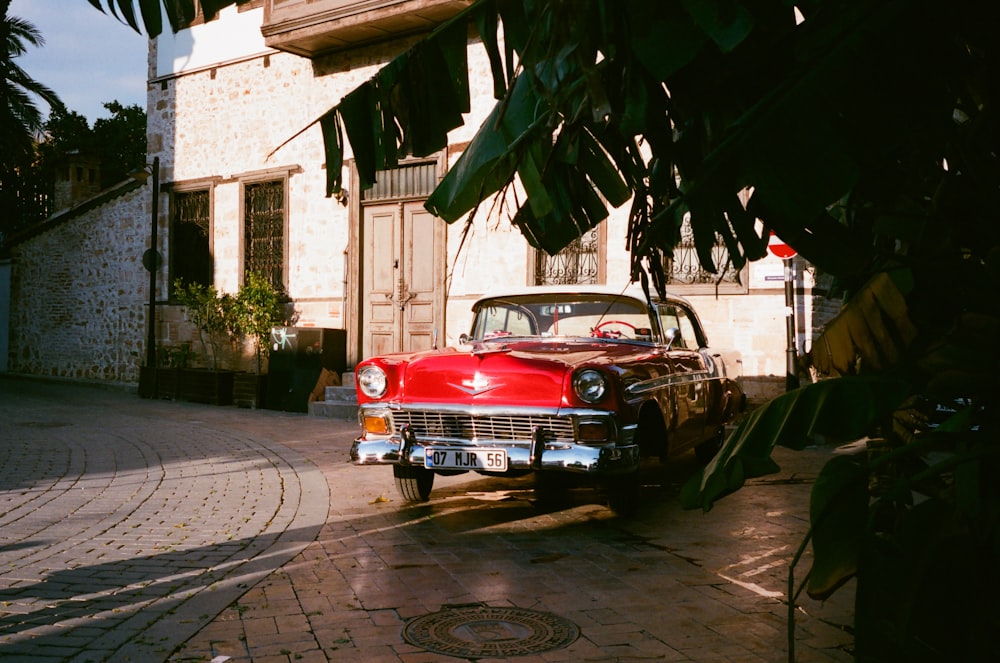 red classic car parked on sidewalk during daytime