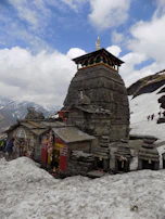 Snow-capped peaks surrounding the ancient Kedarnath temple, with pilgrims braving the cold.