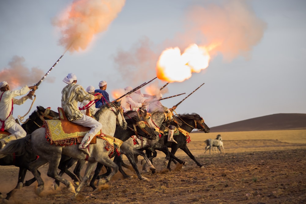 people riding horses on brown field during daytime