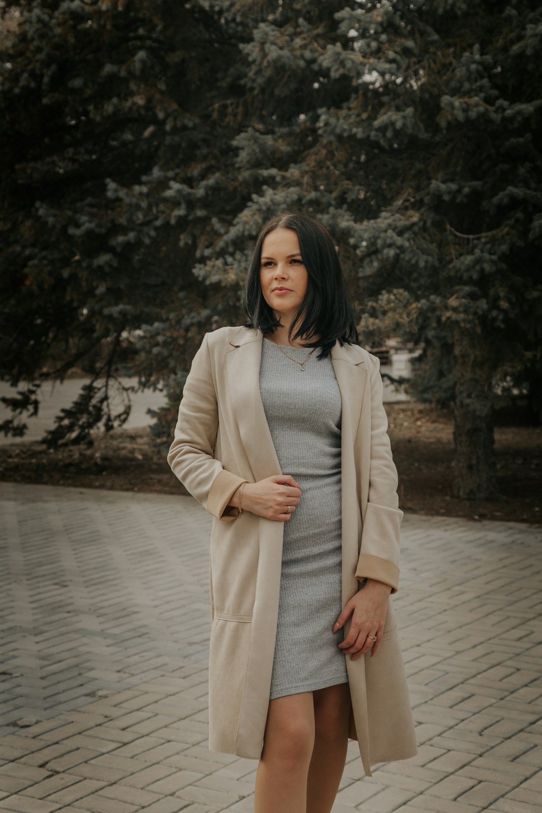 woman in white coat standing on gray concrete pavement