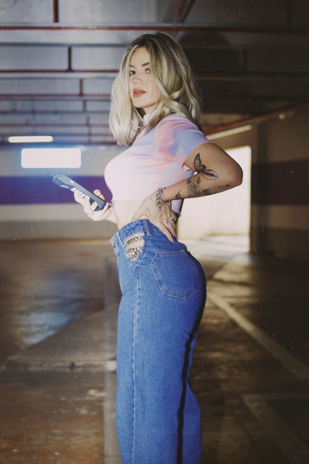 woman in white t-shirt and blue denim jeans holding white smartphone