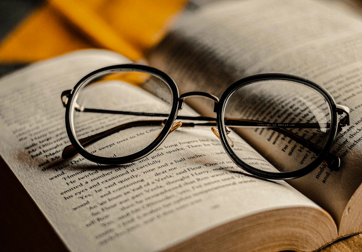 Óculos de leitura sobre um livro aberto, em luz natural
